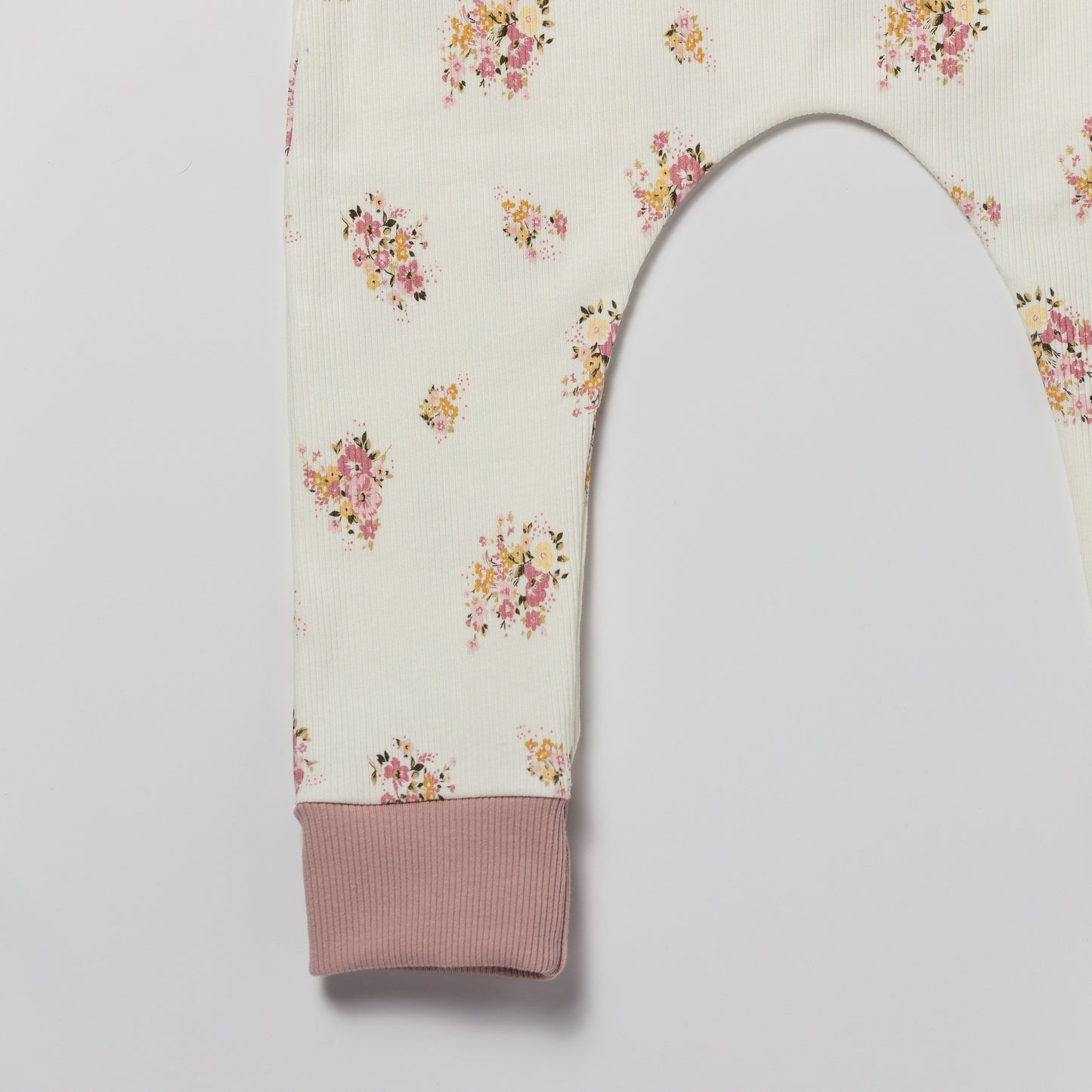 Floral patterned baby and children’s romper with pink accents on a white background
