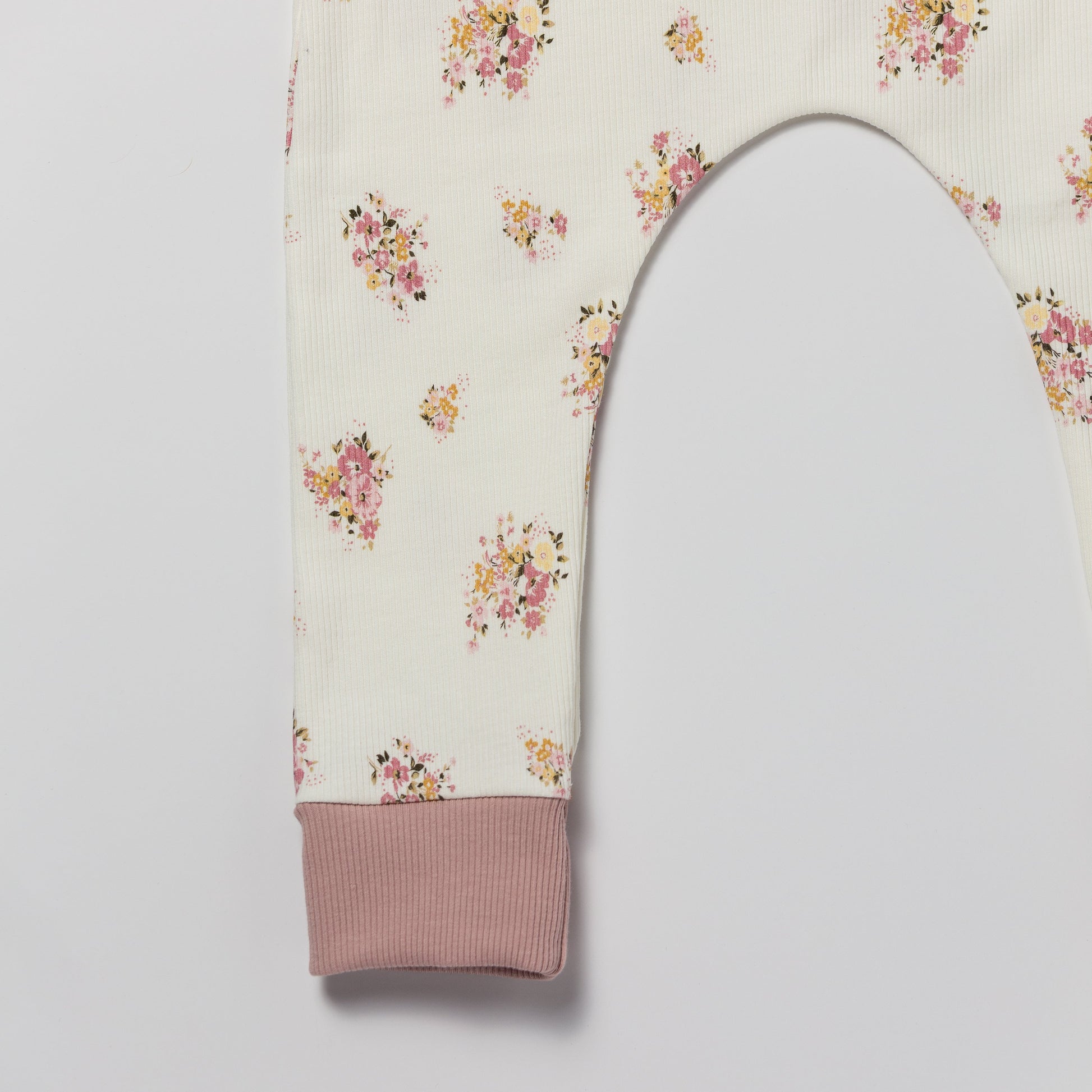Floral patterned baby and children’s romper with pink accents on a white background 